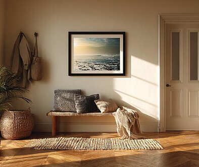 朝の柔らかな光が差し込む玄関に、ハワイの海のアートが飾られたインテリア。木製ベンチとクッション、観葉植物が並ぶ落ち着いた空間。